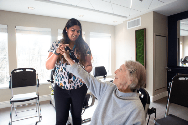 A young woman holding a pet while interacting with an elderly person indoors.