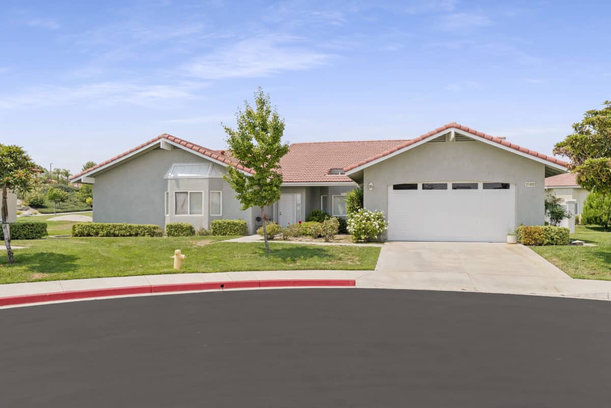 A suburban single-story house with a garage and a well-maintained lawn.