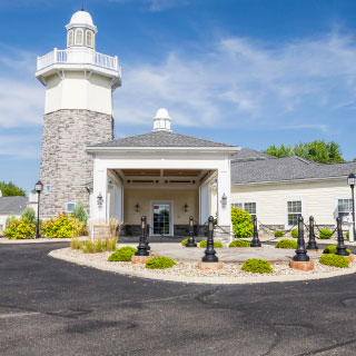 A charming resort entrance featuring a lighthouse design, surrounded by well-maintained landscaping under a clear blue sky.
