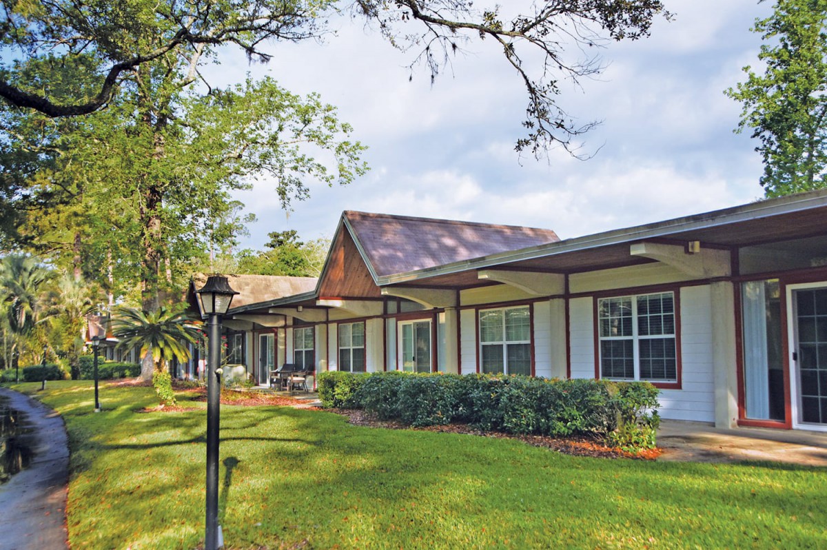 A suburban house with a well-maintained lawn and surrounding trees.