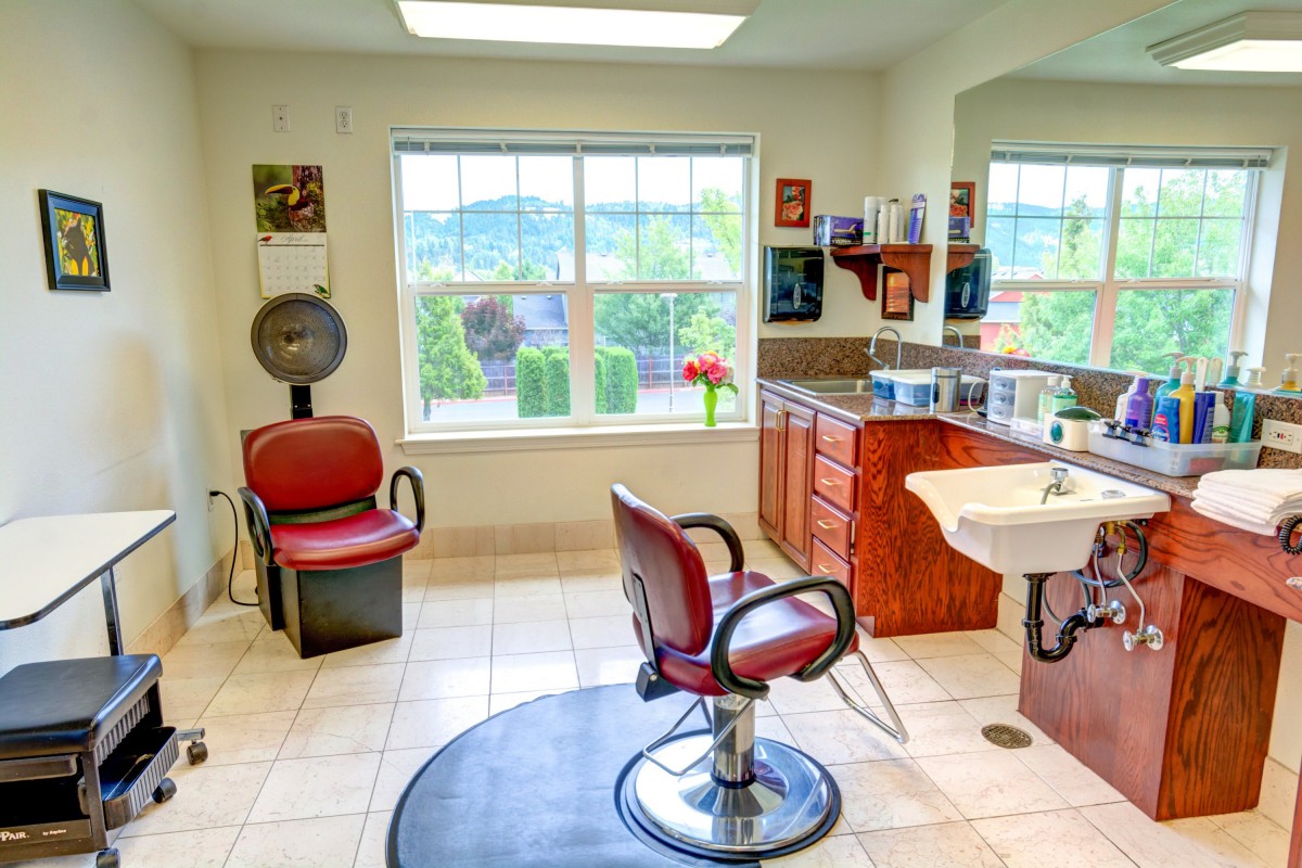 An interior view of a bright hair salon with barber chairs and a sink.