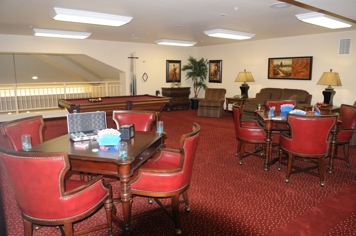 A cozy lounge area featuring red chairs and tables, with artwork on the walls and warm lighting.