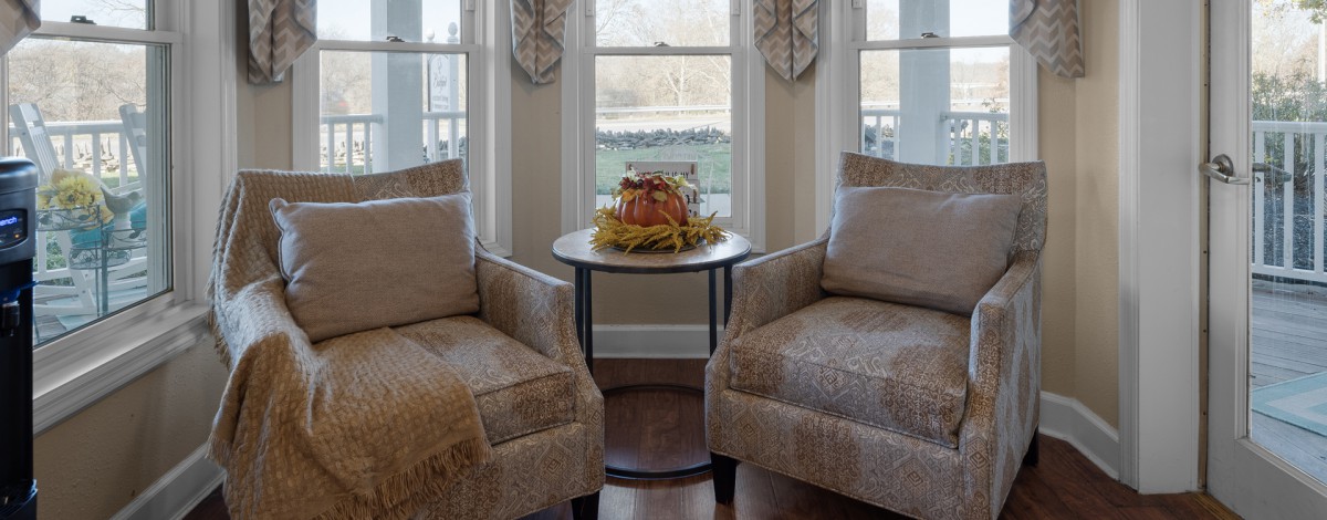 A cozy living room setup with two armchairs and a decorative table centerpiece by the windows.