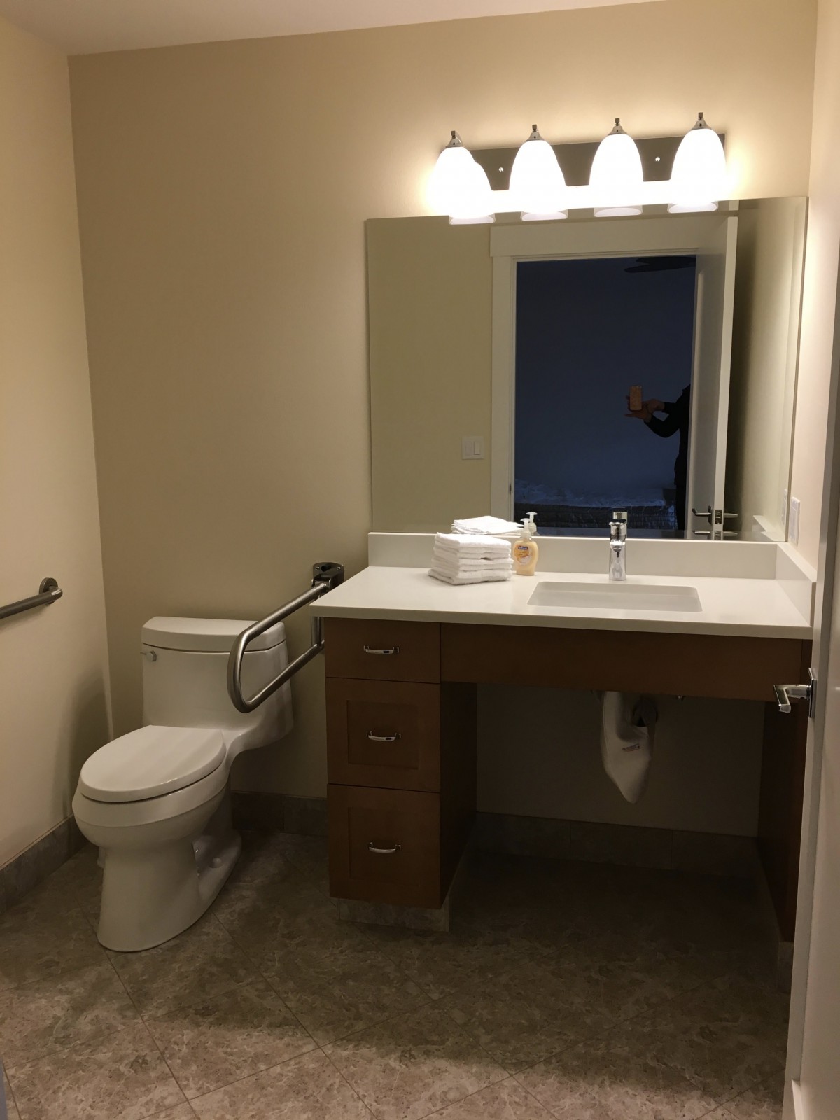 A bathroom featuring a sink, toilet, and mirror with overhead lighting.