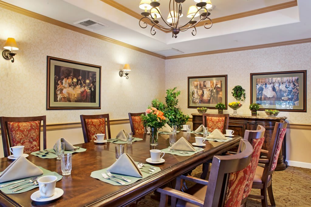 A well-decorated dining room with a large table set for a meal, featuring elegant place settings and artwork on the walls.