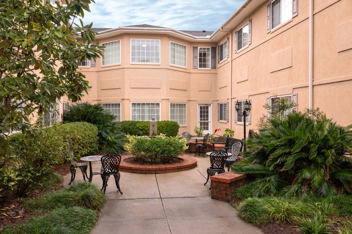 A charming courtyard with outdoor seating and lush landscaping in front of a multi-story building.