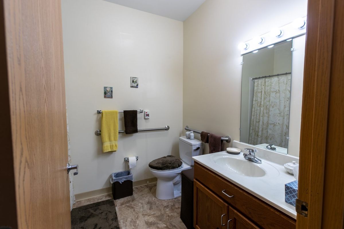 A clean and well-organized bathroom featuring a sink, mirror, and toilet.