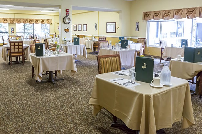An elegant dining room setup with tables, chairs, and menus.