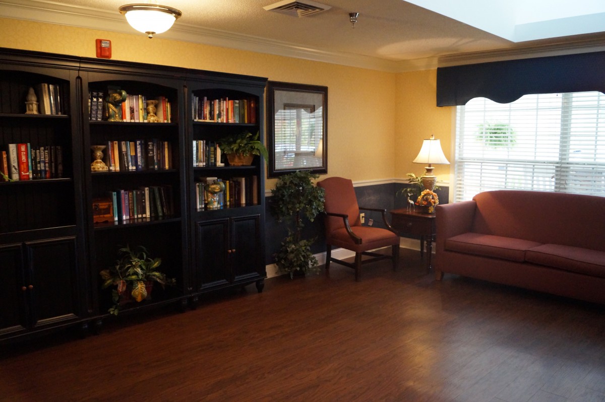 A cozy reading area with a bookshelf, armchair, and a lamp.