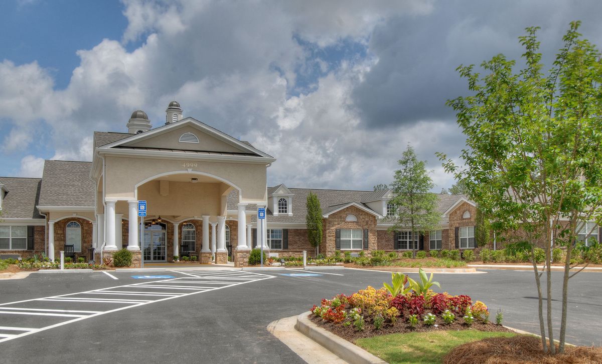 A beautifully landscaped building entrance under a cloudy sky.