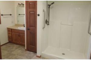 A bathroom featuring a walk-in shower, wooden cabinet, and sink.