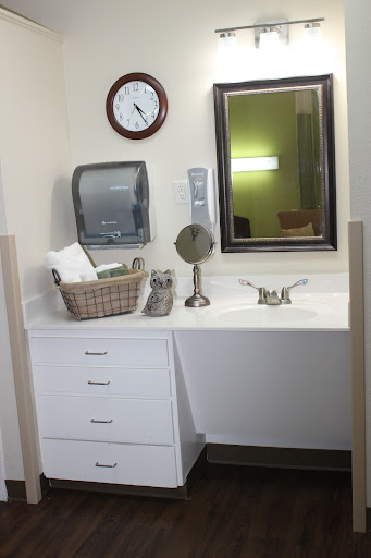 A clean and organized bathroom sink area featuring a mirror, clock, and neatly arranged towels.