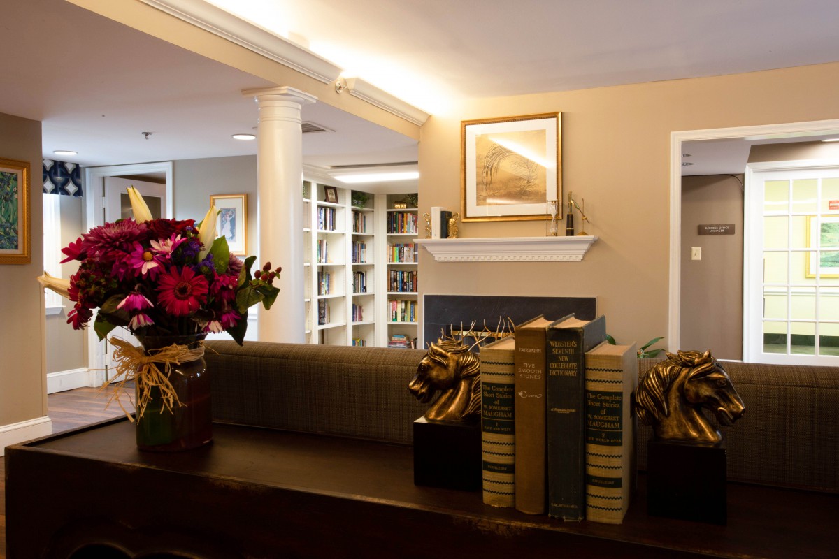 A cozy library interior with bookshelves and flower arrangements.