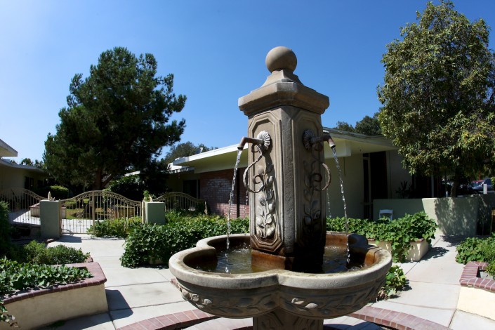 A decorative outdoor fountain with ornate designs in a sunny garden setting.
