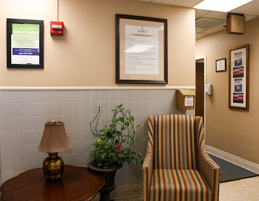 A cozy waiting area featuring a striped chair, lamp, and decorative plant.