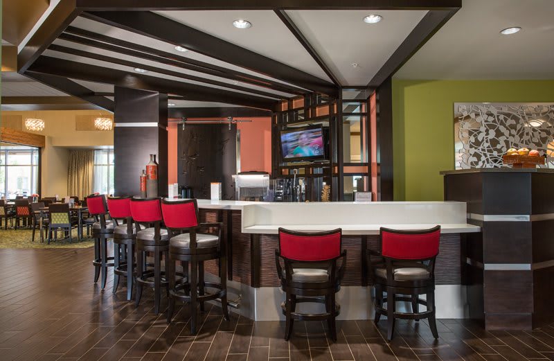 A modern bar interior featuring red chairs and a sleek design.