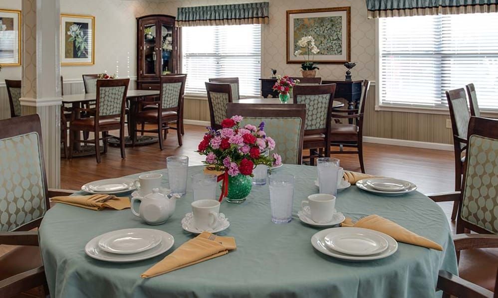 A well-decorated dining room with a table set for four, featuring colorful flowers as a centerpiece.