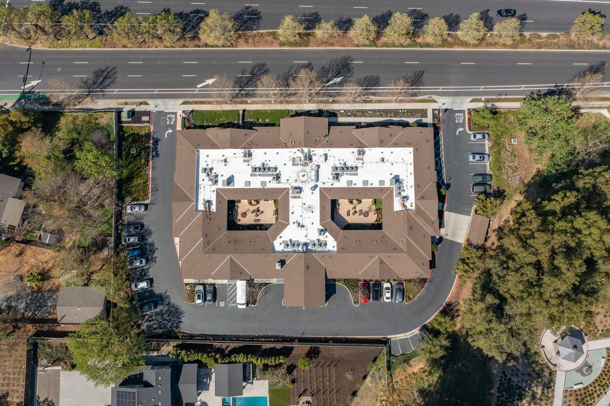Aerial view of a building with a distinct roof design and surrounding parking area.