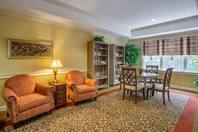 A cozy living room with armchairs, bookshelves, and a table set by the window.