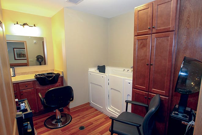 A multifunctional room featuring washing machines and a salon station with a sink, mirror, and chairs.