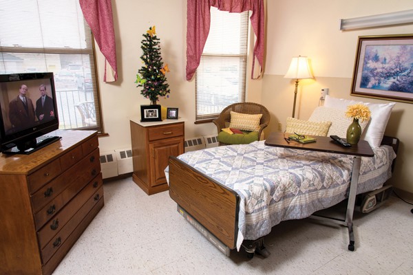 A cozy room featuring a hospital bed, wooden furniture, and warm decor.