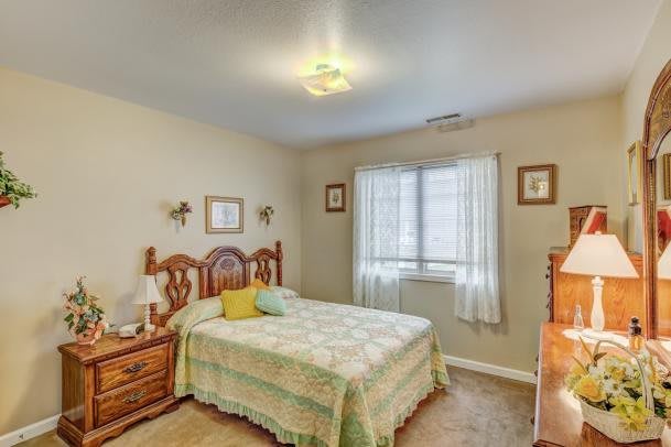 A cozy bedroom with a wooden bed, side tables, and a window with curtains.