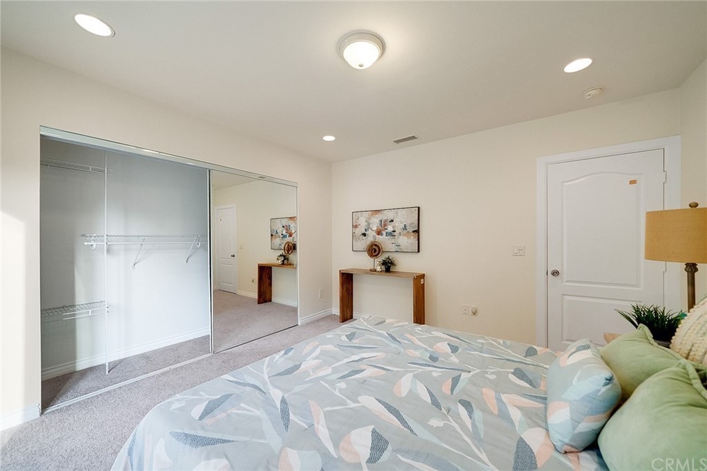 A modern bedroom featuring a cozy bed, mirrored closet doors, and tasteful wall art in soft neutral tones.