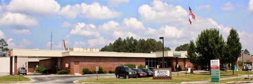 An exterior view of a school building surrounded by lush greenery and a clear sky.