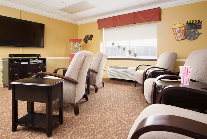 A cozy room with comfortable chairs and a television, featuring a popcorn machine by the window.