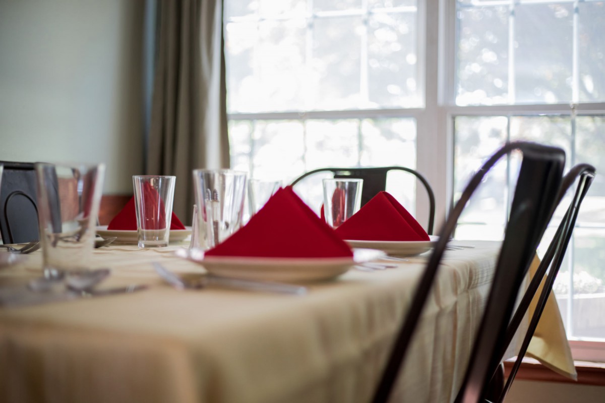 A neatly set dining table with red napkins and glassware.