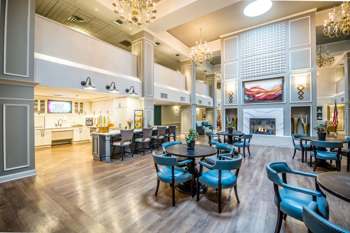 A spacious and modern hotel lobby with elegant chandeliers, comfortable seating, and a fireplace.