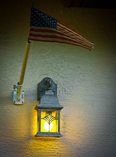 An illuminated lantern beside an American flag, enhancing the charm of the home exterior.
