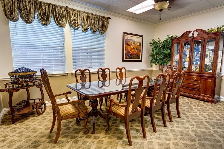 A traditional dining room featuring a large wooden table with matching chairs, elegant drapery, and tasteful decor.