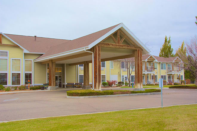 A view of a building with a covered entrance and surrounding landscape.