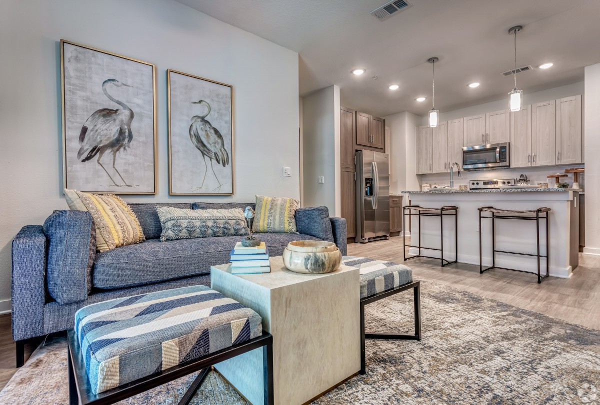A modern living room and kitchen area featuring stylish artwork, comfortable seating, and contemporary design elements.
