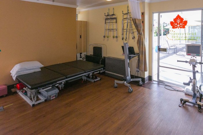A rehabilitation room equipped with a therapy bed and exercise equipment.