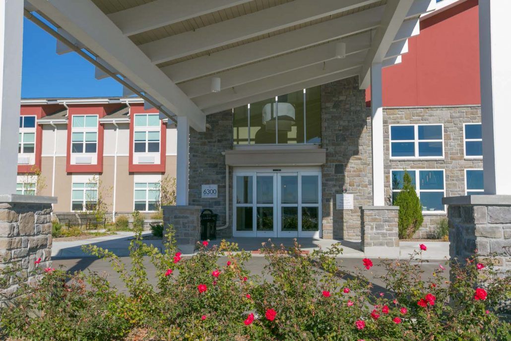 A modern building entrance surrounded by landscaped flowers.