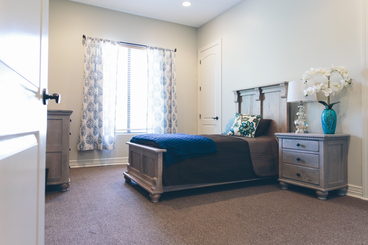 A cozy bedroom featuring a wooden bed, nightstand, and decorative curtains.