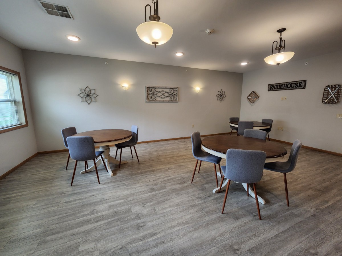 A modern dining room with round tables and upholstered chairs under elegant lighting.