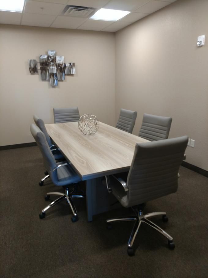 A modern conference room with a long meeting table and six chairs.