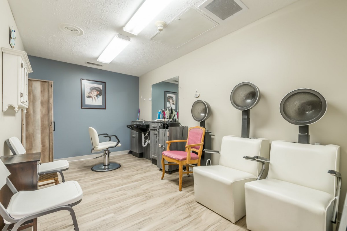 A modern beauty salon with comfortable chairs and hair drying equipment.