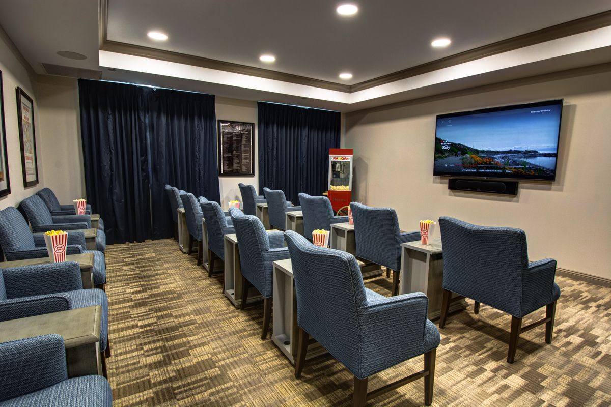 A well-arranged conference room featuring rows of chairs facing a large screen, suitable for meetings or presentations.
