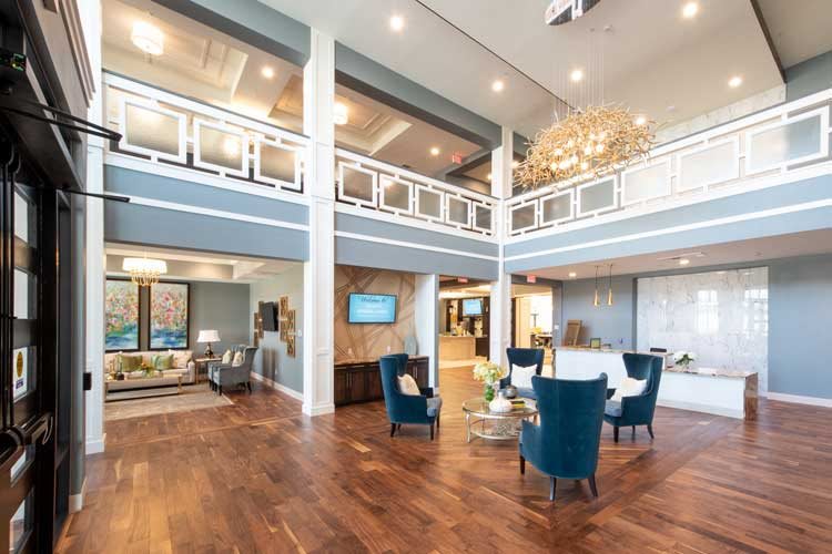 A modern and spacious living room with elegant decor, featuring a large chandelier and stylish furniture.