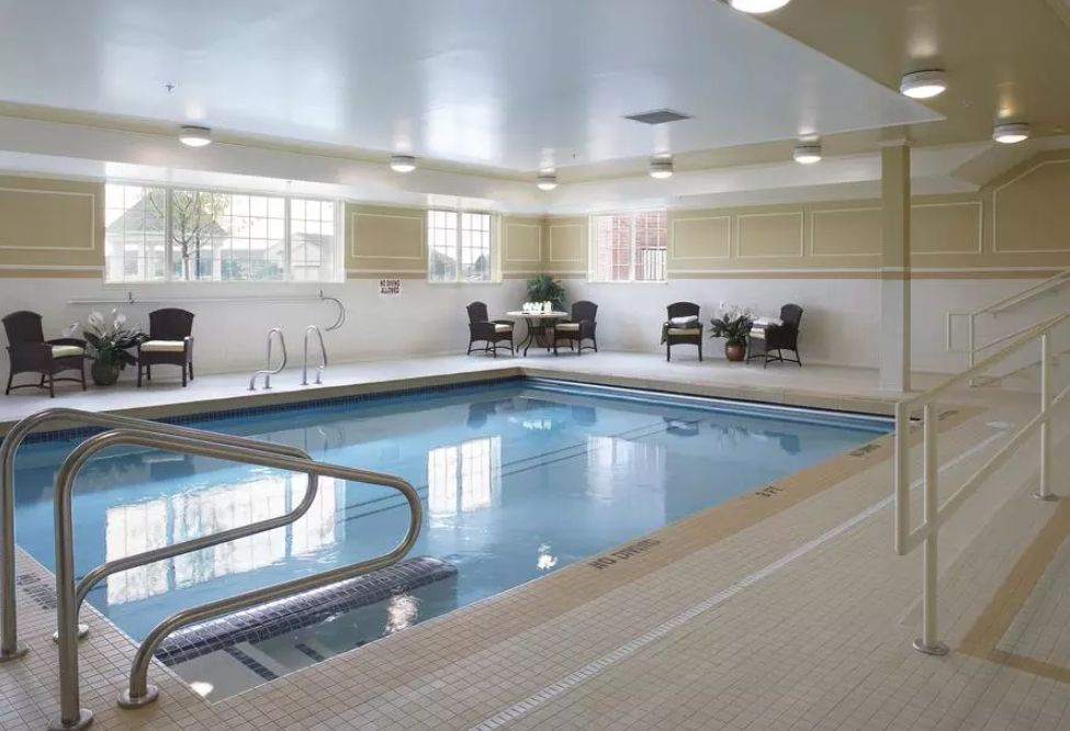 An inviting indoor swimming pool with seating and tables for relaxation.