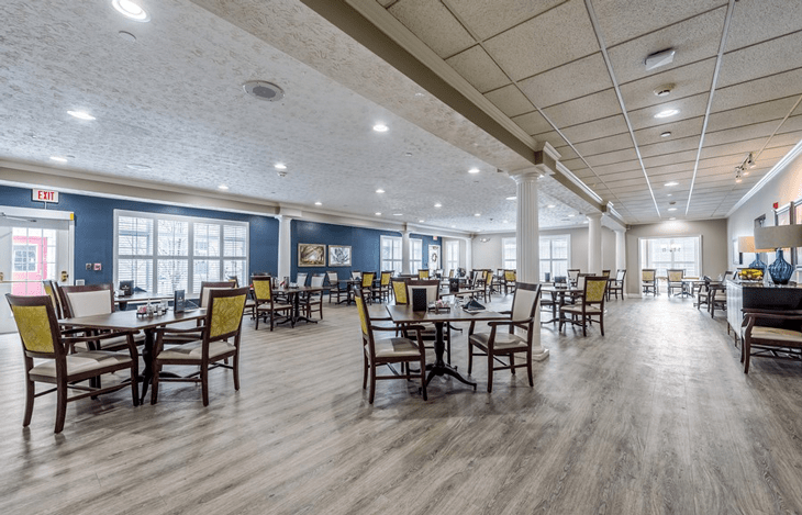 A spacious dining area with neatly arranged tables and chairs, featuring large windows and modern lighting.