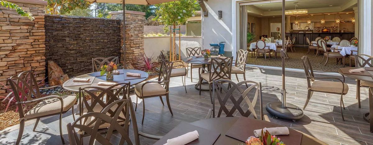 A sunny patio with outdoor seating at a restaurant, featuring tables and chairs.