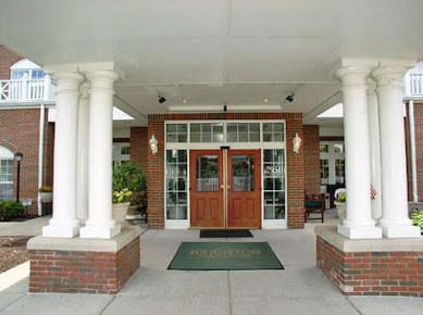A building entrance with columns and double wooden doors.