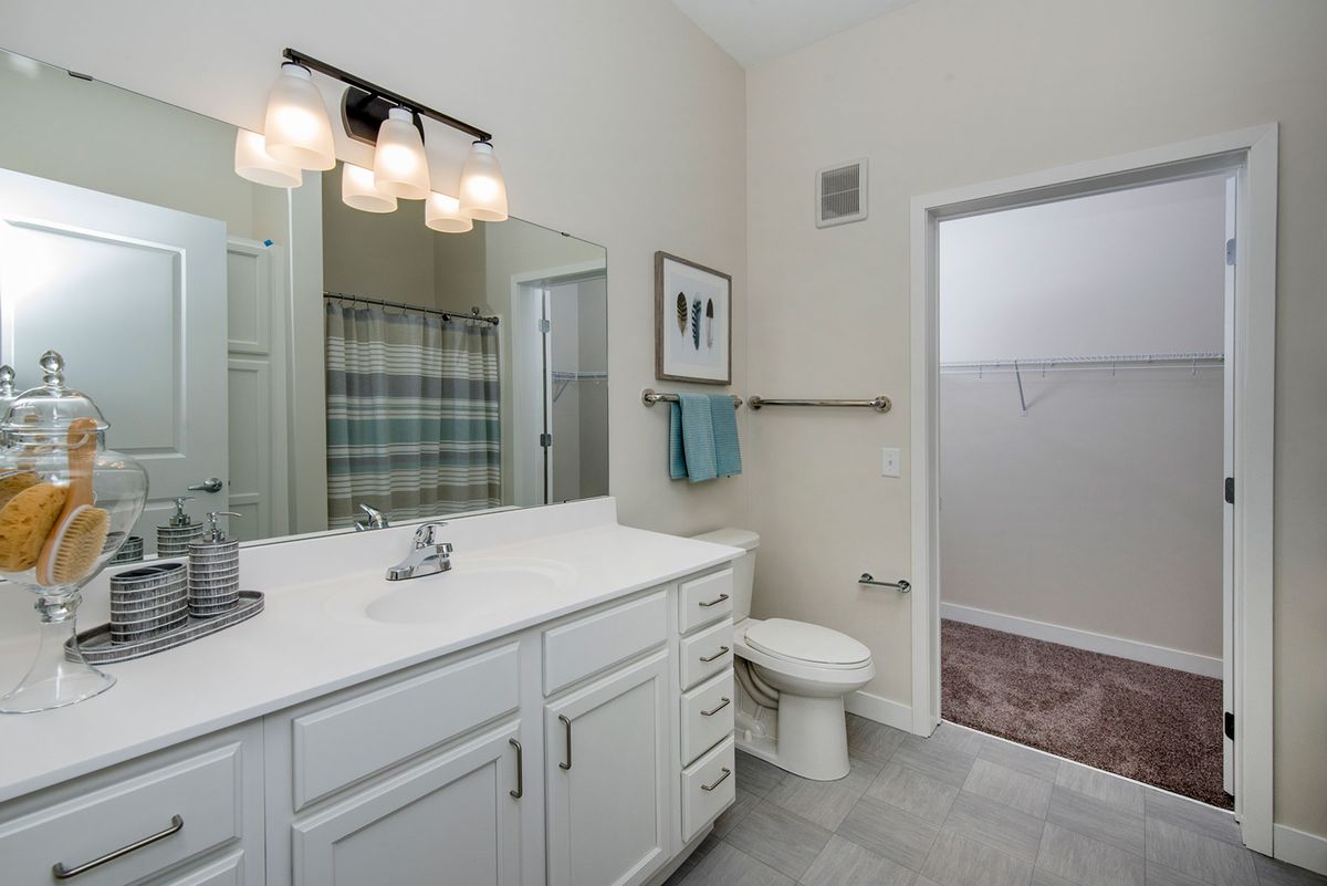 A modern bathroom with a clean white countertop, mirror, and shower area.