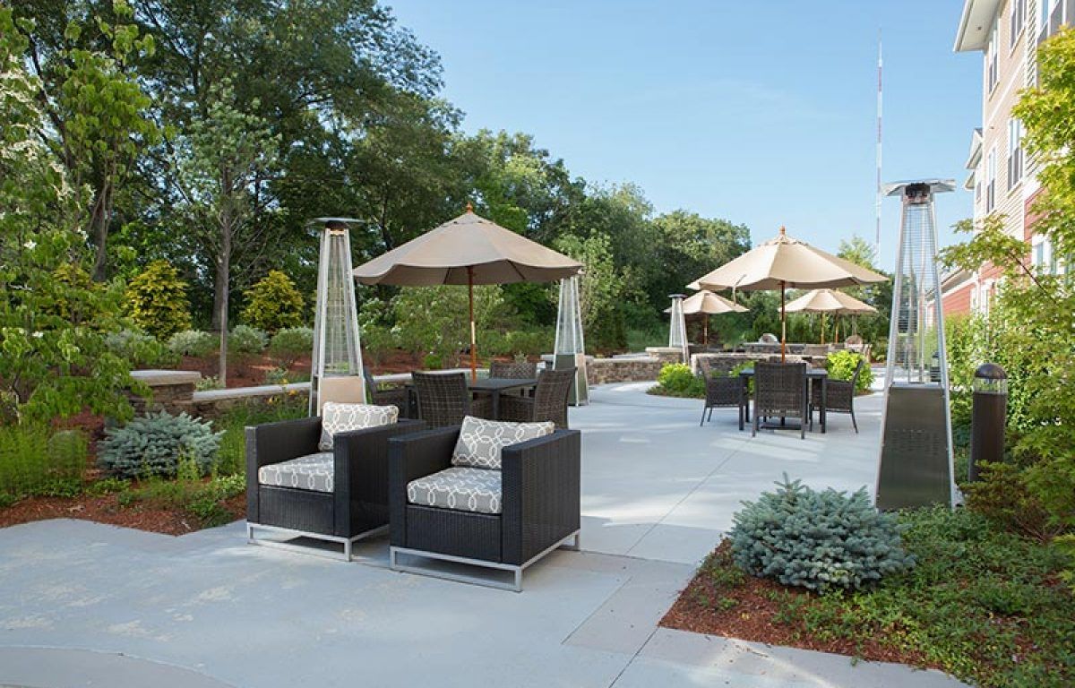 A well-furnished patio with comfortable seating and umbrellas on a sunny day.
