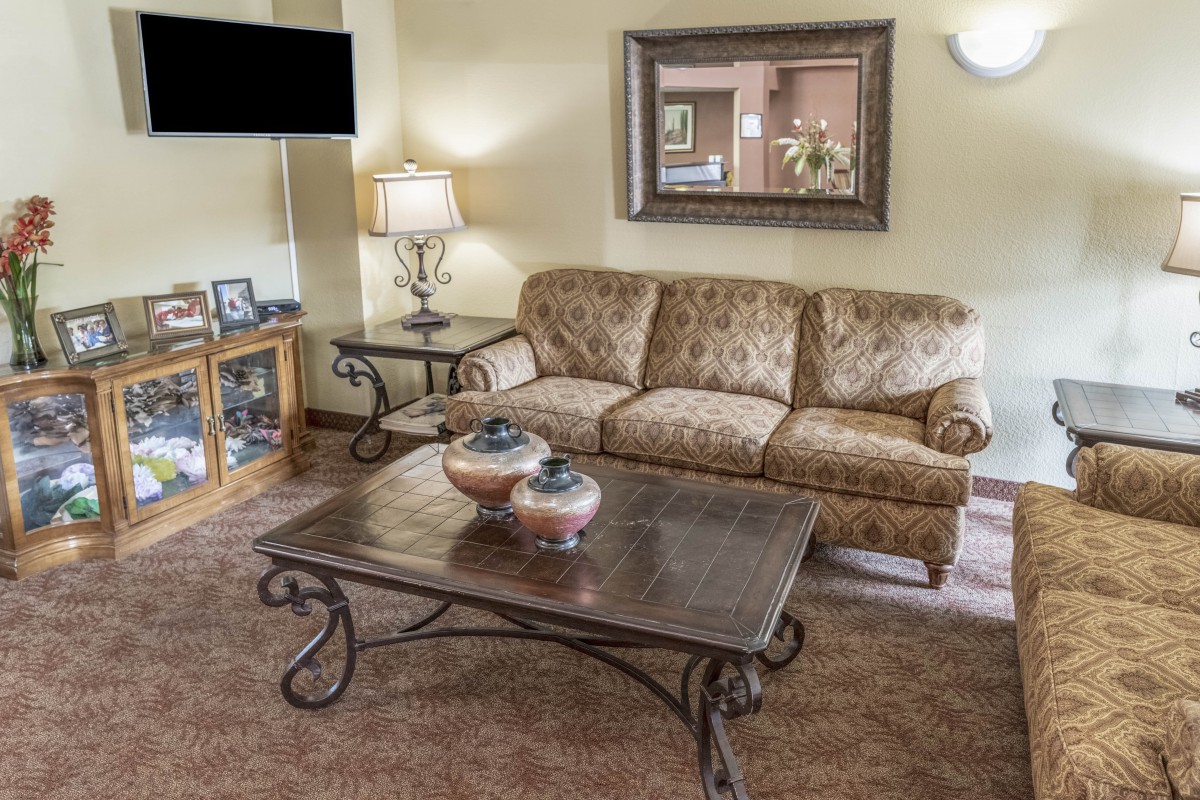 A cozy living room with a sofa, coffee table, and lamp, featuring warm decor.